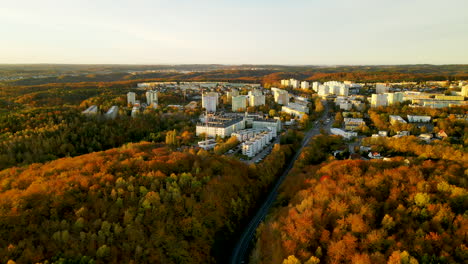 Aerial-backward-on-Witomino-in-Gdynia,-autumn-season-with-warm-color-of-trees-and-bright-high-buildings