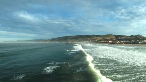 Flying-just-above-the-point-where-the-waves-break-toward-the-landmark-pier-at-Pismo-Beach