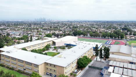Crenshaw-High-school,-bad-area-of-Los-Angeles,-South-Central-community,-overlooking-city,-rising-aerial