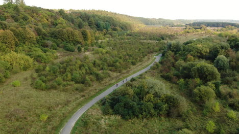 Team-of-cyclist-ride-on-majestic-countryside-road-in-Lithuania,-aerial-drone-view