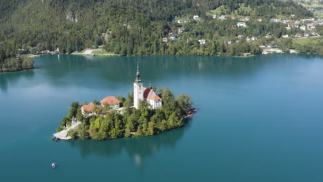 Scenic-view-on-Bled-Lake-with-a-church-dedicated-to-the-Assumption-of-Mary-on-a-small-island,-Julian-Alps,-Slovenia---aerial-drone-shot