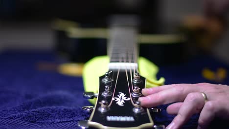 Restringing-and-cleaning-a-beautiful-black-single-cutaway-accoustic-guitar---restringing-is-complete,-so-we-give-the-guitar-a-final-polish-with-a-duster