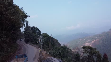 Aerial-shot-of-North-Bengal-hill-station,-slow-pan-shot-of-cars-and-trucks-passing-on-road-and-mountains