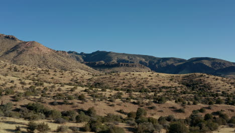 Low-aerial-view-moving-horizontally-through-arid-desert-landscape,-4K