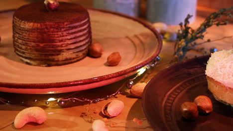 Köstlicher-Schokoladenkuchen-Und-Kokosnuss-Eclair-In-Tellern-Mit-Auf-Dem-Tisch-Verstreuten-Nüssen