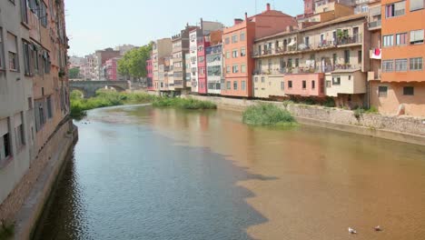 Bunte-Häuser-Entlang-Des-Flusses-Onyar-In-Der-Nähe-Der-Brücke-In-Girona,-Katalonien,-Spanien