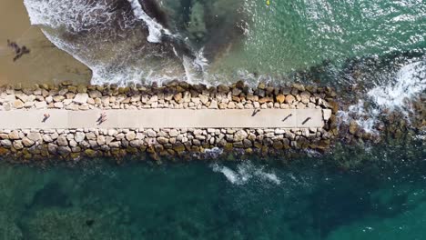 Aerial-top-dowwn-view-of-old-ruined-pier-on-the-beach-with-tourists