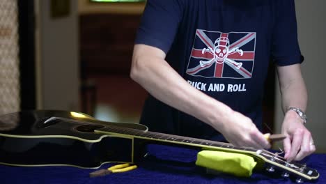 Restringing-and-cleaning-a-beautiful-black-single-cutaway-accoustic-guitar---removing-the-excess-lengths-of-the-strings-from-the-headstock-using-a-pair-of-snips