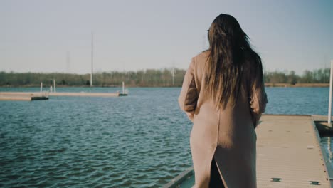 Footage-of-a-woman-walking-along-a-lake-dock-on-a-chilly-day-at-sunset