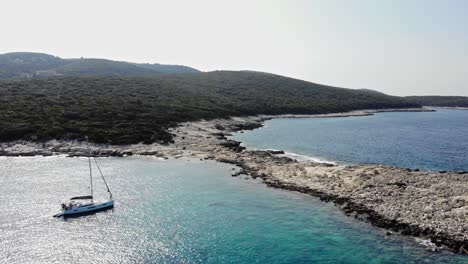 Sailboat-Floating-In-Glistening-Waters-Of-Emplisi-Beach-At-Summertime-In-Greece