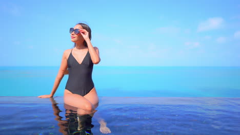 Slender-Exotic-Woman-in-Swimsuit-on-Infinity-Pool-With-Endless-Blue-Tropical-Horizon-in-Background,-Full-Frame