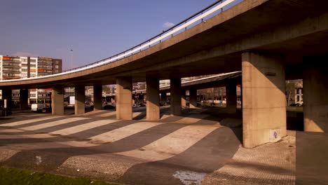 Aerial-sideways-movement-through-large-concrete-overpass-columns-of-highway-intersection-in-urban-surrounding