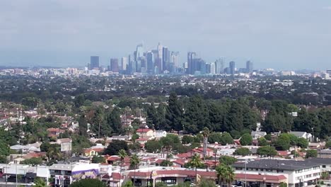 Drone-View-of-Hazy-Skyline-of-Downtown-Business-District-Los-Angeles-from-Residential-Suburbs,-Parallax-Established-Shot