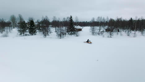 Man-Driving-A-Snowmobile-Through-The-Thick-Snow-During-Winter-Season-In-Muonio,-Finland-Near-Lapland