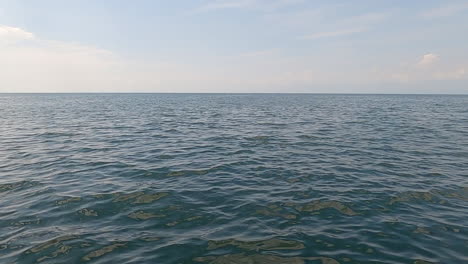 Flat-horizon-line-on-large-body-of-water,-lake-or-ocean,-wispy-cloud