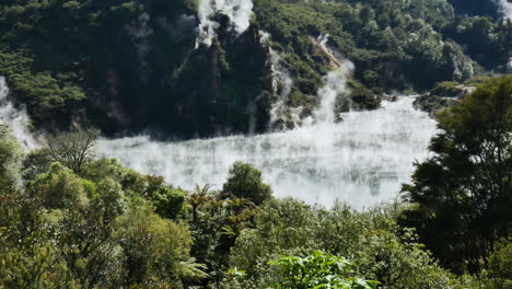 Wide-shot-of-flying-Sulfur-Steam-over-Frying-Pan-Lake-in-green-wilderness-of-New-Zealand-during-summertime