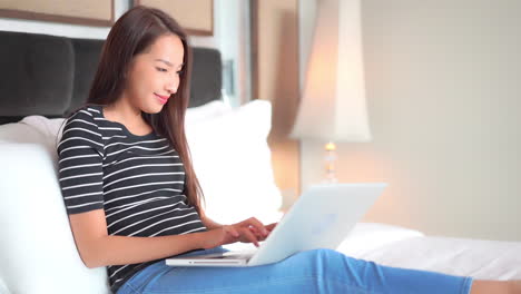 Junge-Asiatin,-Die-Während-Der-Sperrung-Online-Auf-Einem-Laptop-Aus-Dem-Schlafzimmer-Arbeitet