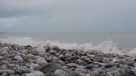 Foaming-white-waves-washing-into-calming-serene-rocky-pebble-stone-beach-coastline