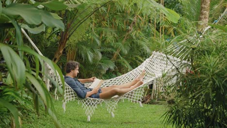 Young-man-lying-in-hammock-reading-a-book