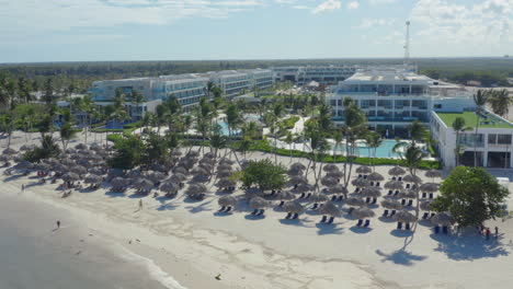 Palmeras-Y-Sombrillas-De-Paja-En-La-Playa-Del-Lujoso-Hotel-Resort
