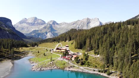Luftüberführung-über-Den-Oeschinensee-In-Kandersteg,-Schweiz,-Mit-Booten-Auf-Dem-Türkisfarbenen-Wasser-Neben-Klippen-An-Einem-Sonnigen-Sommertag
