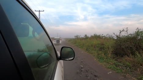 Three-white-vehicles-drive-in-convoy-on-lowland-dirt-road-in-Africa