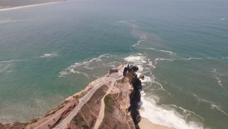 Aerial-High-view-Seascape-Landmark-Lighthouse-on-cliffside,-Nazaré---Portugal