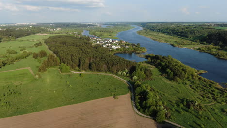 Pedestrian-pathway-winding-through-Lithuanian-flatlands-near-majestic-river,-aerial-view