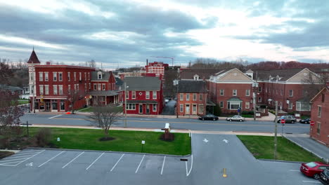 Wide-aerial-rising-reveal-of-traffic-driving-through-old-small-town-in-East-Coast-USA-city,-Elizabethtown-Pennsylvania