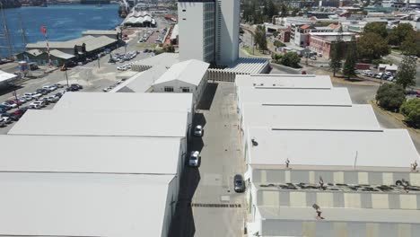 An-onward-moving-aerial-shot-above-white-warehouses-built-beside-each-other-in-a-row