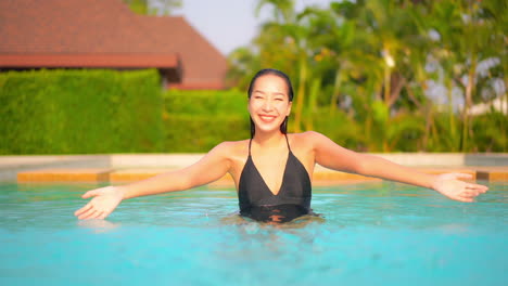 Mujer-Tailandesa-Asiática-Dentro-De-La-Piscina-Salpicando-Agua-Con-Ambas-Manos,-Vacaciones-Exóticas-En-Un-Hotel-En-Tailandia