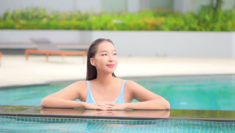Junge-Attraktive-Asiatische-Frau,-Die-Sich-An-Der-Poolgrenze-Lehnt-Und-Ihren-Tropischen-Urlaub-Genießt