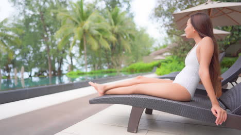 Slender-Asian-Woman-on-Pool-Chair-at-Poolside-of-Luxury-Tropical-Resort,-Full-Frame
