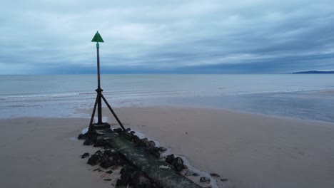 Coastal-tide-marker-aerial-view-low-slow-push-in-right-across-moody-overcast-low-tide-seaside-beach