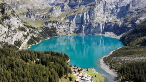 Aerial-flyover-towards-the-turquoise-lake-Oeschinensee-in-Kandersteg,-Switzerland-on-a-sunny-summer-afternoon