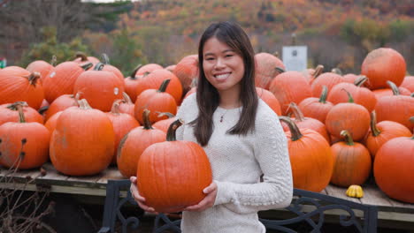 Attractive-young-Asian-woman-holding-a-pumpkin-and-smiling