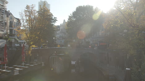 Static-view-of-bridge-over-beautiful-canal-in-Utrecht,-the-Netherlands-with-a-bright-sun-flaring-in-camera-lens