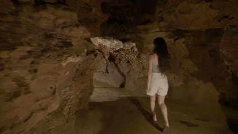Tracking-following-shot-of-young-woman-exploring-the-ancient-geological-limestone-cave-of-Saint-Cezaire