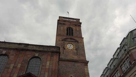 Manchester,-UK-St-Ann's-Church-with-English-flag-waving-in-the-wind-on-a-cloudy-day
