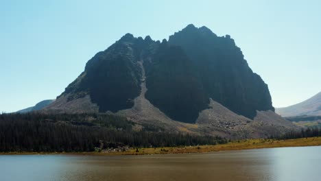Stunning-aerial-drone-landscape-nature-dolly-in-shot-of-the-beautiful-Lower-Red-Castle-Lake-with-the-Red-Castle-Peak-looming-behind-surrounded-by-pine-trees-in-the-High-Uinta-national-forest-in-Utah