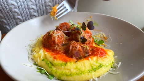 Eating-tasty-meatballs-with-creamy-polenta,-microgreens-and-cheese,-delicious-food-on-a-plate,-lunch-dinner,-4K-shot