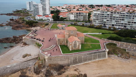 Saint-Nicolas-medieval-priory-and-Sables-d'Olonne-cityscape-with-skyscraper,-aerial-view