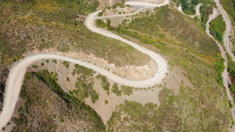 High-angle-aerial-view-of-two-vehicles-touring-winding-road-with-curves