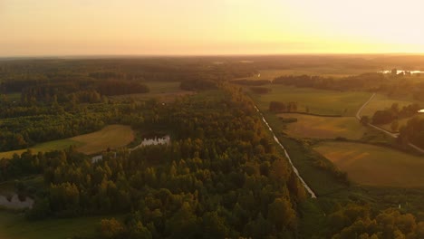 Land-of-forest-and-agriculture-during-golden-hour,-aerial-drone-view