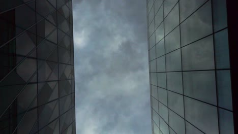 Abstract-shot-of-modern-glass-buildings-looking-up-at-cloudy-sky-cityscape