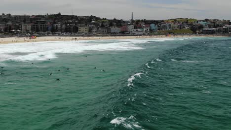 Surfers-waiting-for-big-sea-wave-with-Bondi-Beach-in-background,-Australia