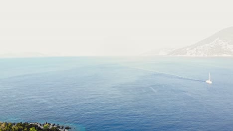 Weißes-Boot-Segelt-Am-Blauen-Ozean-Vom-Aussichtspunkt-Des-Leuchtturms-Von-Fiskardo-Auf-Der-Insel-Kefalonia,-Griechenland