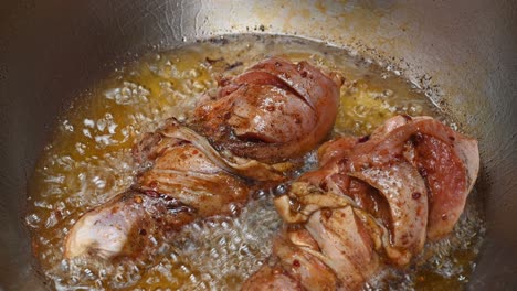Sizzling-oil-frying-two-pieces-of-chicken-to-golden-brown-in-a-stainless-steel-pan