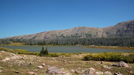 Stunning-Lower-Red-Castle-Lake-up-in-the-High-Uinta-National-Forest-with-barren-mountains,-pine-trees,-and-small-foliage-up-a-ten-mile-backpacking-trail-between-Utah-and-Wyoming