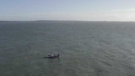 Aerial-flight:-Port-side-of-small-fishing-vessel-on-flat-sea-offshore